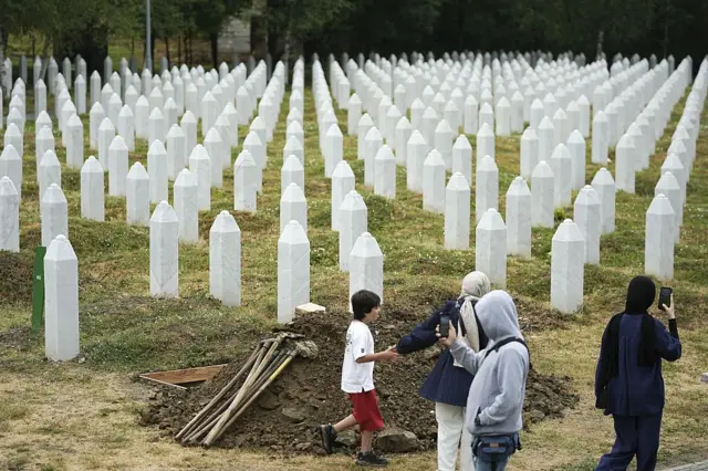Cuatro personas recorren el memorial que recuerda en Potocari a las víctimas de Srebrenica. 