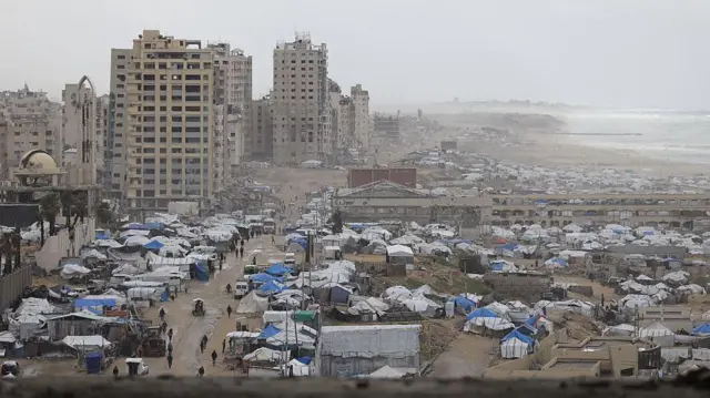 Yıkıntı binalar arasında deniz kıyısındaki kumluk alana kurulu çok sayıda çadırı görüyoruz