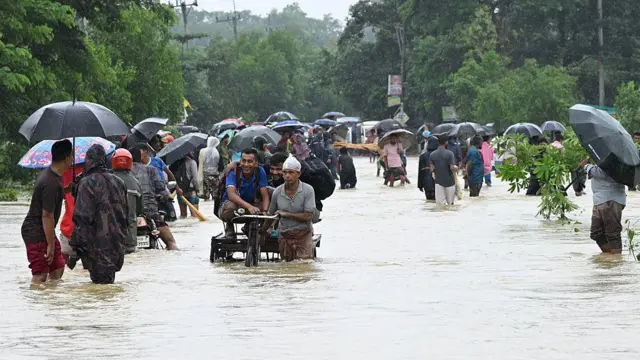 পায়ে হেঁটে বা ভ্যানে চড়ে জলাবদ্ধ সড়ক পার হচ্ছেন চট্টগ্রামের সাতকানিয়ার স্থানীয়রা।