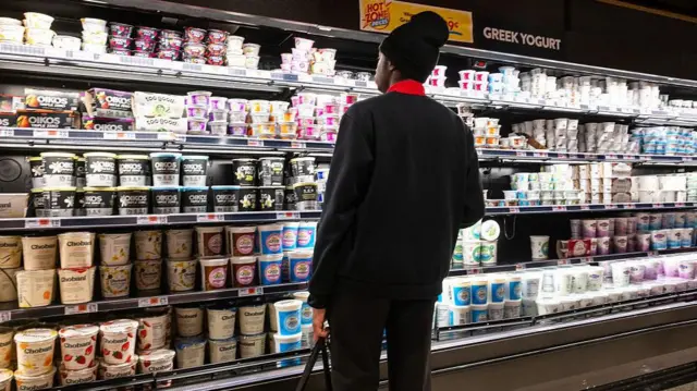 یک خریدار در تاریخ ۲۷ فوریه ۲۰۲۶ در یک فروشگاه مواد غذایی در منهتنِ شهر نیویورک در حال خرید است. آمار تازه منتشرشده از شاخص قیمت تولیدکننده نشان داد که قیمت‌ها در ماه ژانویه برای مصرف‌کنندگان آمریکایی ۰٫۵ درصد افزایش یافته، در حالی که قیمت‌های «هسته‌ای» ۰٫۸ درصد رشد داشته‌اند. این ارقام که از سوی وزارت کار آمریکا منتشر شد، روز جمعه باعث سقوط قابل توجه شاخص‌های اصلی بورس شد. شاون هریس نامزد دموکرات‌ها برای کرسی کنگره در شمال ایالت جورجیا: «چون قیمت بنزین بالا می‌رود، همه‌چیز گران می‌شود...»