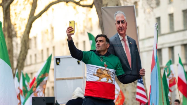 متظاهر يلتقط لنفسه صورة مع لافتة عليها لوحة رضا بهلوي