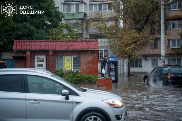 Чоловік на цегляному паркані біля магазину, з усіх боків оточеному водою
