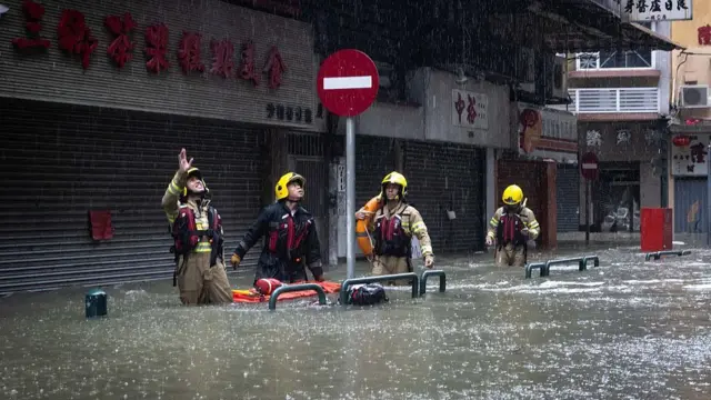 Bomberos caminan por las calles con el agua hasta la cintura.