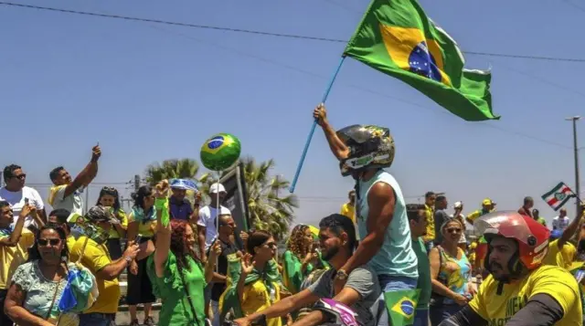 P﻿ara pendukung Bolsonaro memakai kaus dan aksesori kuning-hijau saat menghadiri kampanye.