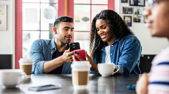 Mexicano mostra o telefone celular a uma jovem