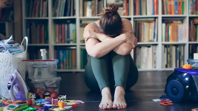 امرأة تجلس على الأرض تحضن رأسها.