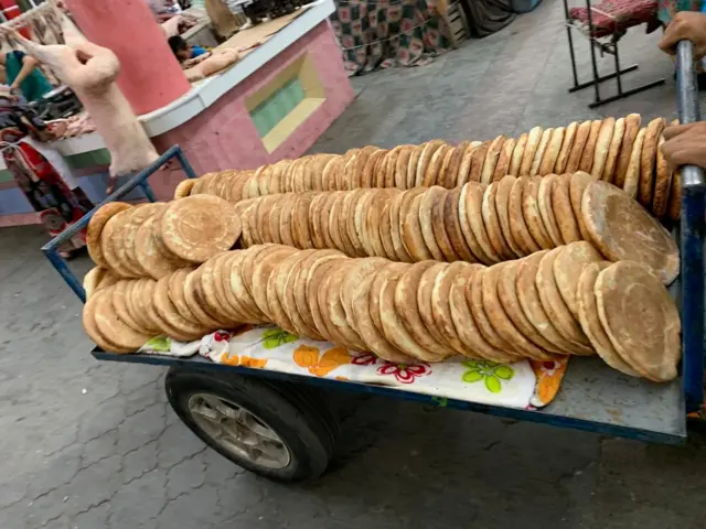 Xujanddagi Payshanba bozorining rastasiga tandirda yopilgan non aravaga uzun taxlangan holda keltirilyapti