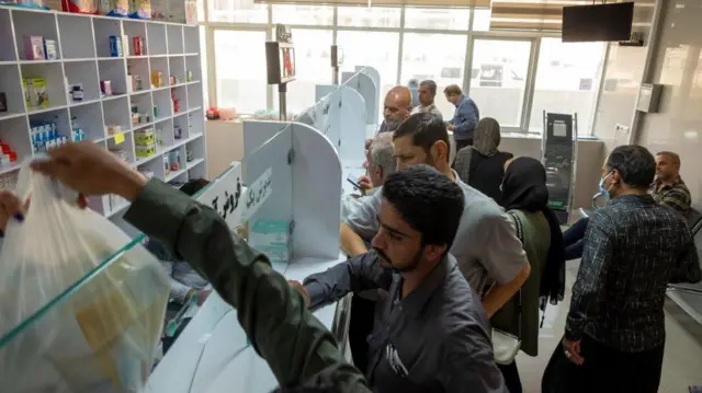 متقاضیان دارو در ۹ اکتبر ۲۰۲۴ در بیمارستانی در نزدیکی شهر شیراز در استان فارس، در حدود ۹۳۲ کیلومتری جنوب تهران، ایران، منتظر دریافت دارو در داروخانه هستند.