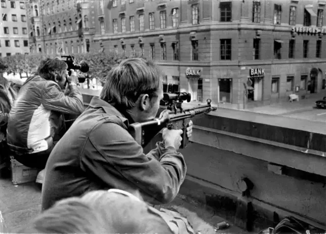 Фотографи і поліцейські снайпери на даху будинку навпроти захопленого банку Kreditbanken у Стокгольмі 24 серпня 1973 року