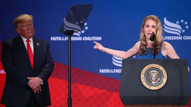 Natalie Harp fala apontando para o presidente Donald Trump, durante conferência realizada em Washington em 2019