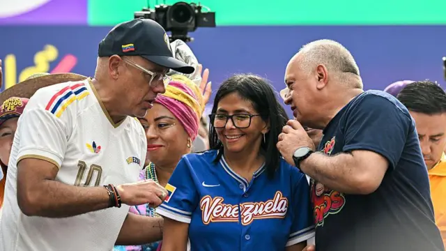 Jorge Rodríguez conversa com Diosdado Cabello, com Delcy Rodríguez entre eles. Nenhum deles está vestido de vermelho