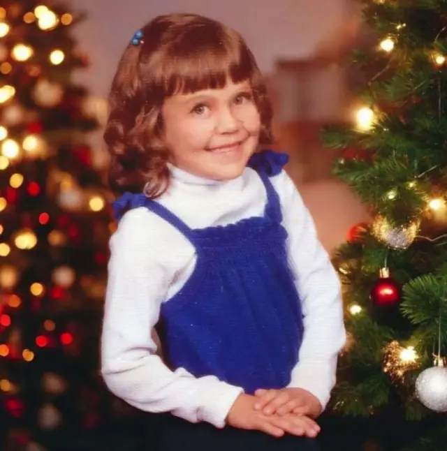 Alexis, aos seis anos, em frente a um árvore de Natal