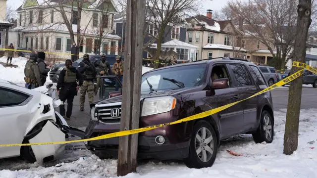 Agentes federais se reúnem ao lado de um veículo com um buraco de bala no parabrisa, após a motorista ter sido baleada por um agente de imigração dos EUA, segundo autoridades locais e federais, em Minneapolis, Minnesota, EUA, em 7 de janeiro de 2026.