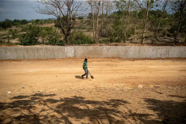 Un hombre camina del lado haitiano junto al muro que separa el país de República Dominicana el 21 de marzo de 2023.