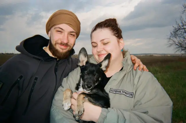 Військовий обіймає жінку, яка тримає в руках собаку 
