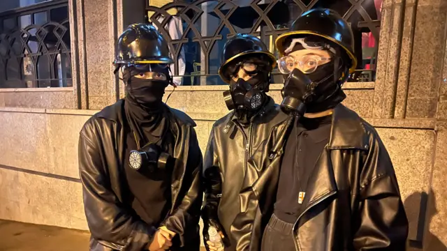 Troje demonstranata u crnonom, sa šlemovima na glavama i gas maskama na licu