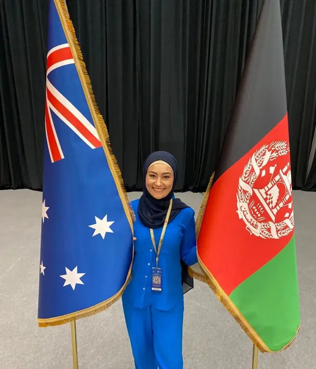 اغلې پيمان د افغانستان او اسټراليا د بیرغونو په منځ کې ولاړه ده. شنې جامې یې اغوستې او ټيکرۍ یې په سر دی.