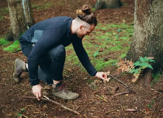 آنتونی مولالی در حال برداشتن قارچ‌هایی که کنار یک درخت روییده‌اند