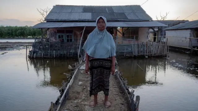Potret warga berdiri di depan rumahnya terkena dampak abrasi air laut di Desa Pantai Bahagia, Kecamatan Muara Gembong, Kabupaten Bekasi, Provinsi Jawa Barat.