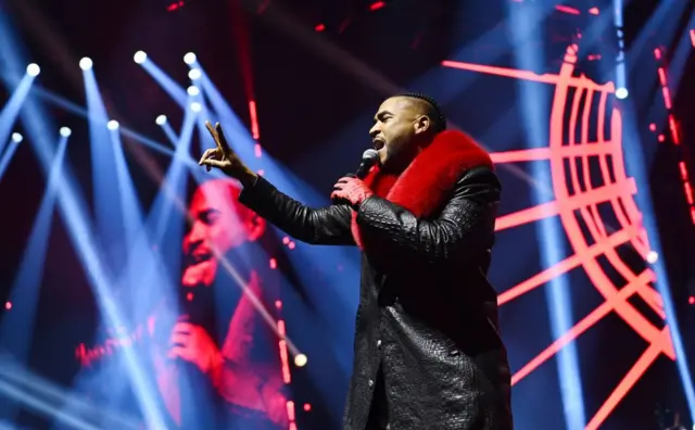 Don Omar, vestido de negro y rojo, cantando en un concierto en el Coca-Cola Coliseum en marzo de 2024 en Toronto, Ontario.