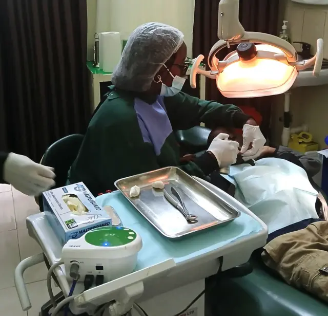 Muganga w'amenyo Uwamaliya arimo yita ku murwayi