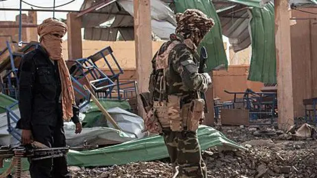 Man cover im face, carry gun, anoda make on military uniform dey im side
