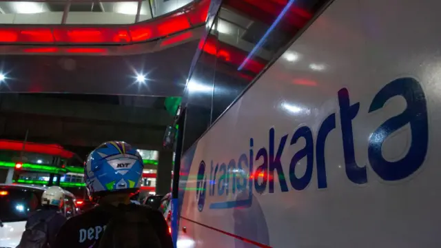 Seorang pengemudi di sebelah bus TransJakarta di tengah kemacetan. 