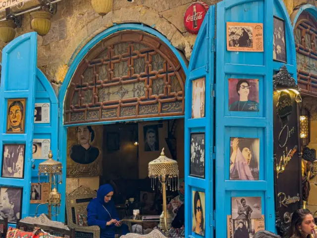 People sit at a cafe that has high ceilings and domed blue doors.