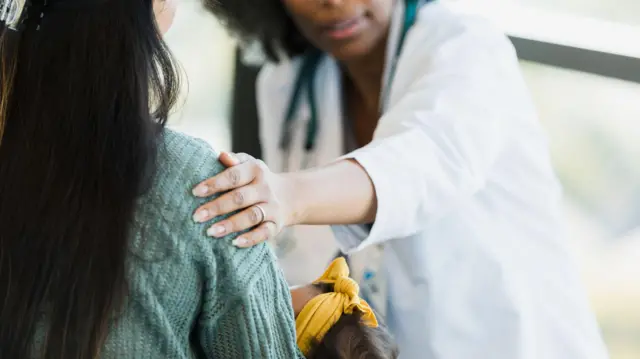 Médica conversando com mãe que segura um bebê