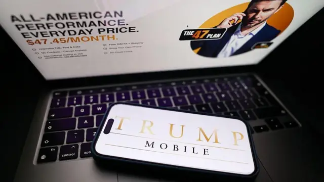 ラップトップのキーボードに、「トランプ・モバイル」と書かれた画面が映ったスマートフォンが載っている。ラップトップの画面には、同事業の料金プランが表示されている