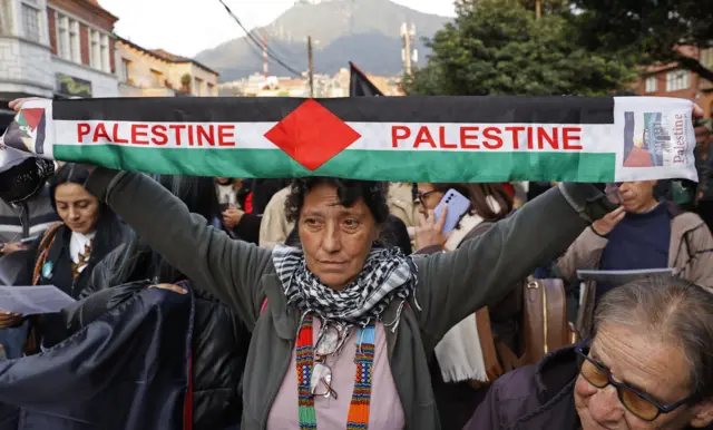 Otu nwaanyị ji ọkọlọtọ mba Palestine nọro n'etiti ndị ngagharịiwe na Bogota, Colombia