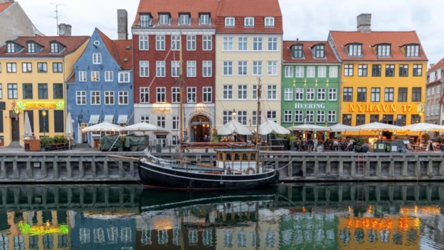 نمایی از رودخانه و یک قایق و ساختمانهای رنگی در آنسوی رودخانه