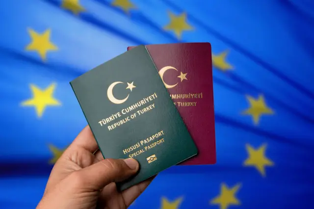 AB bayrağının önündeki yeşil ve bordo Türk pasaportları. 