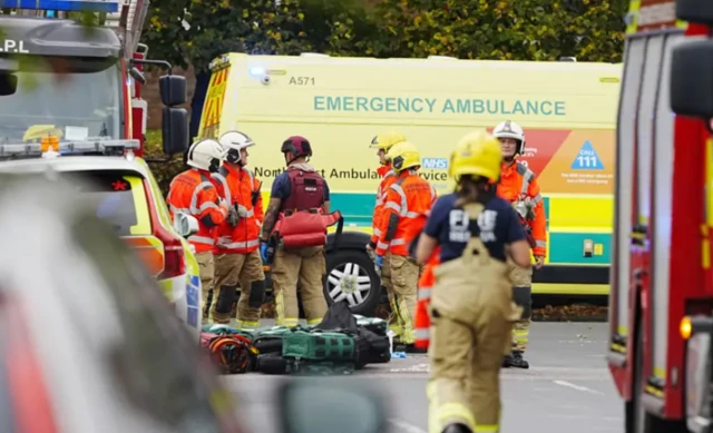 Viaturas e pessoas caminham ao redor de corpo no chão, em Manchester, na Inglaterra