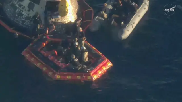 Астронавтов перемещают из капсулы на плот-трап