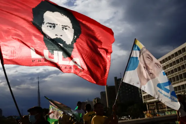 Bandeiras com as imagens de Lula, à esquerda, e Jair Bolsonaro, à direita, tremulam durante ato de campanha.