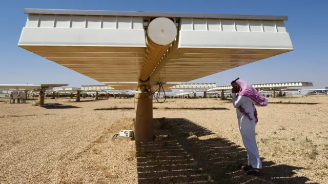 Мужчина в традиционных одеждах под солнечной панелью в аравийской пустыне