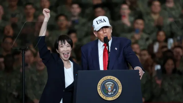 美国总统特朗普（右）与日本首相高市早苗（左）在横须贺美军基地向驻日美军发表讲话，高市早苗兴奋地举起右手，一脸雀跃（28/10/2025）