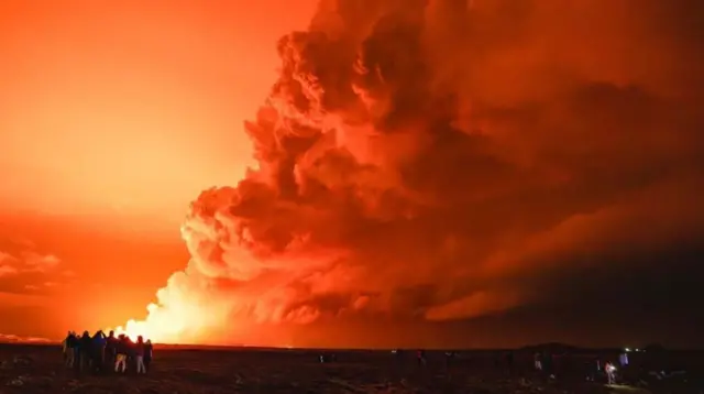 噴火と溶岩流の様子を見る人たち