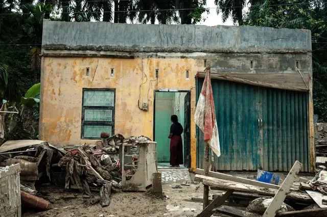 Seorang perempuan di Aceh melihat rumahnya yang rusak dihantam banjir dan longsor akhir November tahun lalu.