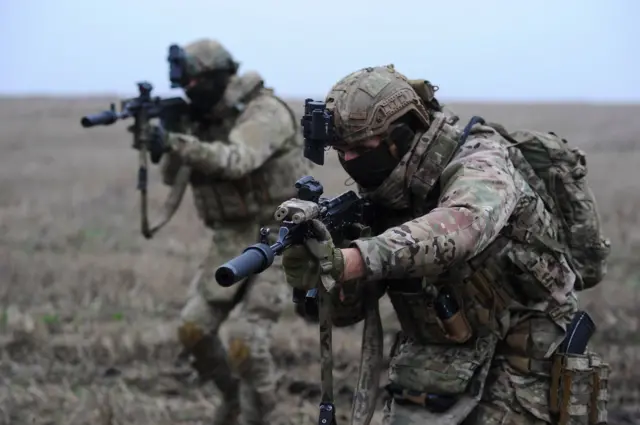 Двое украинских солдат с автоматами идут в атаку