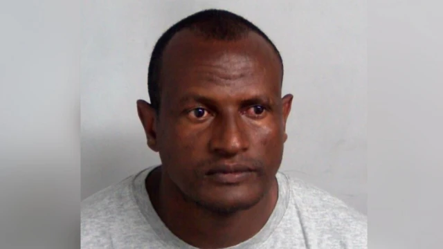 グレーのトレーナーを着用し、黒髪を刈り上げた男性の、身柄拘束時の顔写真