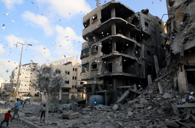 Gazatíes cerca de edificios destruidos en Gaza