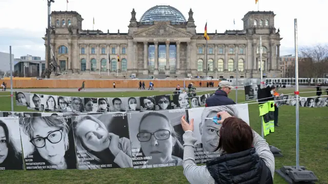 أحد النشطاء يزيل صورًا بالأبيض والأسود لمرضى كوفيد طويل الأمد في ألمانيا بعد مظاهرة في اليوم العالمي للتوعية بفيروس كورونا المستجد