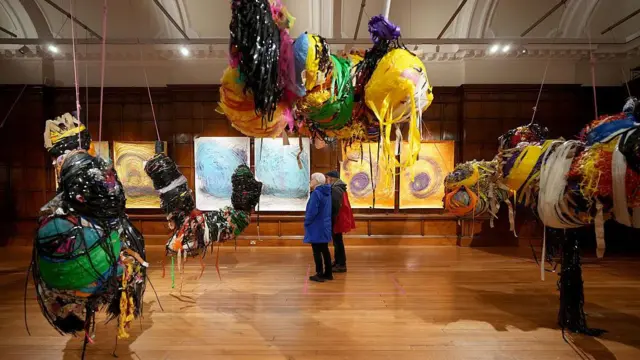 چند اثر هنری در یک گالری هستند و دو نفر آن‌ها را تماشا می‌کنند