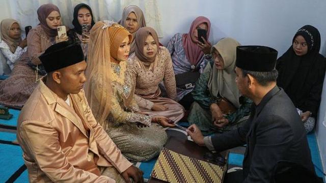 Kepala Kantor Urusan Agama (KUA) Kuta Alam Erman Jaya (kanan) membimbing pasangan pengantin sebelum melaksanakan akad nikah di KUA Kuta Alam, Banda Aceh, Aceh, Jumat (1/3/2024).