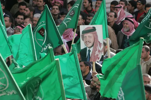 أردنيون يلوحون بأعلام الإخوان المسلمين ويحملون صورة العاهل الأردني الملك عبد الله الثاني خلال مظاهرة في عمان ضد الإغلاق الإسرائيلي المستمر لقطاع غزة، 14 ديسمبر/كانون الأول 2007