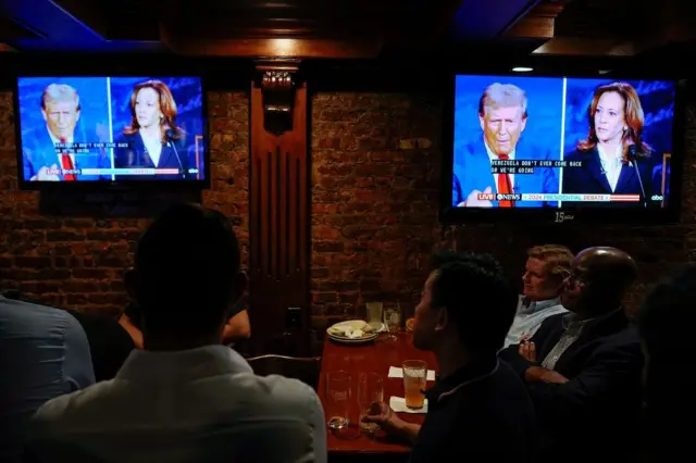 Pessoas assistem a debate em bar