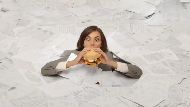 নারী দুই হাতে ধরে একটি বার্গার খাচ্ছেন