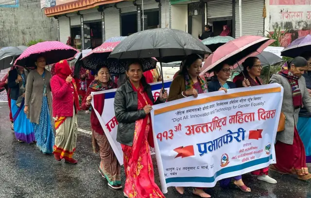पर्वतमा छाता बोकेर नारी दिवसको प्रभातफेरीमा सहभागी हुँदै महिलाहरू
